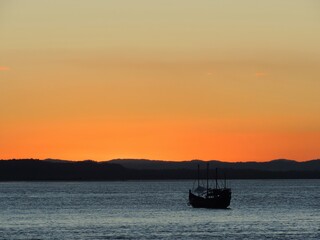 Sunset over the river with caravel boat silhouette and an orange sky during the golden hour
