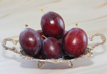 natural red plum fruits in a decorative plate