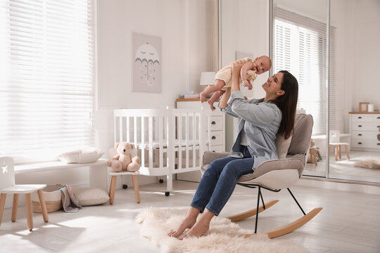 Happy young mother with her cute baby in rocking chair at home