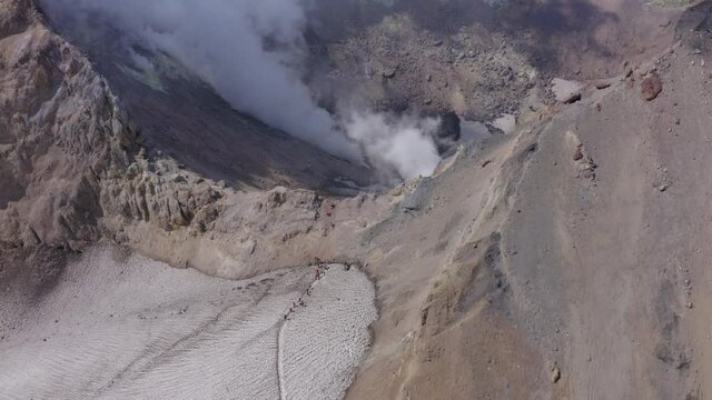 People hiking on Mutnovsky volcano crater with fumaroles and glacier