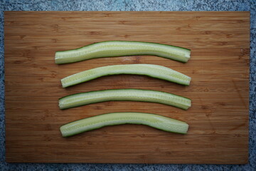 quartered lengthways cucumber lies on a wooden cutting  board