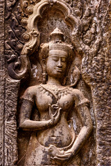 Fototapeta na wymiar Detail of bas relief sculpture the wall of the ancient Ta Prohm temple in the Angkor Thom Area, Siem Reap, Cambodia.