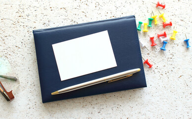 Business card lying on a blue notebook next to the glasses.