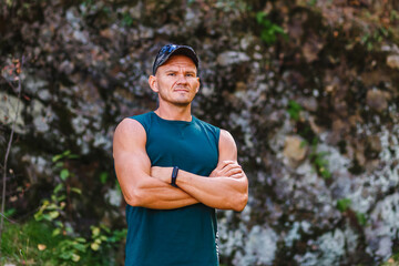strong muscular man in a green sleeveless shirt stands against a cliff in the fall. freedom and...