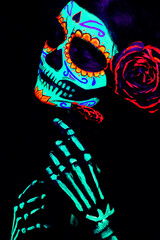 Young girl in the image of Santa Muerte (Saint death or Sugar skull) with bright make-up. Studio...