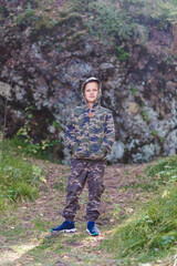 nine-year-old boy in a toast and a khaki hood stands tall on a hike in the mountains in the fall.