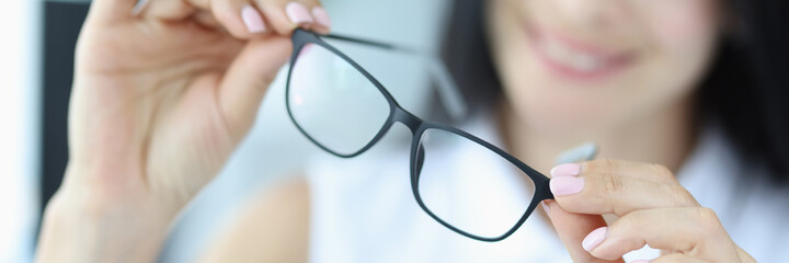 Young woman holds black glasses for vision in hands