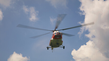 Fototapeta na wymiar Emergency service helicopter flying against clouds