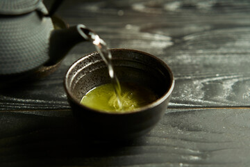 Japanese organic matcha green tea in cup on black wood background. Healthy product from the nature...