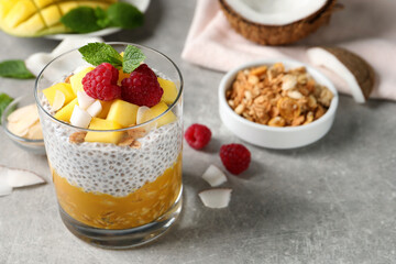 Delicious chia pudding with mango, raspberries and granola on light grey table