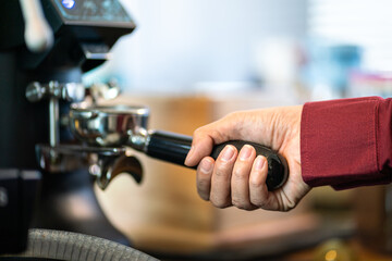 Action of a coffee barista 's hand is taking coffee bean from automatic grinding machine. Food and drink making action photo.