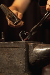 Close-up working powerful hands of male blacksmith forge an iron product in a blacksmith. Hammer,...