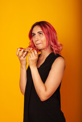 a girl of European nationality greedily looks at a piece of pizza wants to eat it on a yellow background with a place for the text