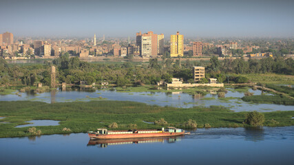 Empty cargo ship passing by Sohag city in the morning. Dry bulk carrier sailing in the Nile river, Egypt