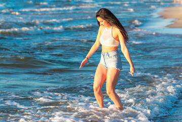 Fototapeta premium Young woman playing in the sea.woman enjoying in sea water .Cheerful young woman having fun on the summer beach.