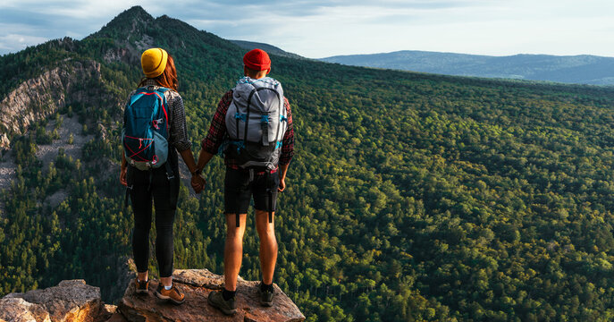 A traveling couple in the mountains. A man and a woman on the background of a mountain, a panorama. Climbing the mountain. Hiking in the mountains. Active recreation in the national park. Copy space