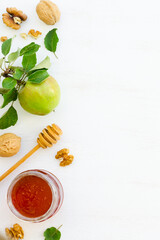 Honey, apples and walnuts on white wooden background
