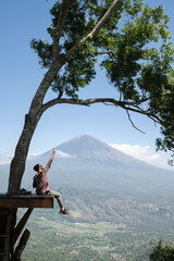 A man traveler admires the mountain - the Agung volcano from a height.
