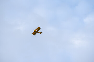 A small vintage biplane flying into clear blue sky