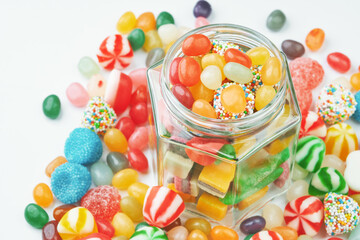 Jar with gummy candies and sweets around on a white background.