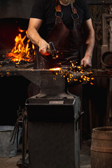 Cropped shot of man, blacksmith working on creating handmade metal product at family smithy....