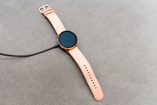 Charging of Smart Watch on a cauch. copy space gray blurred background.