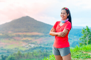 Half-body photo of a female trail runner wearing pink runner, sportswear, smiling, looking at the camera. on the gravel ground on a high mountain with a happy mood, Behind is a mountain view.