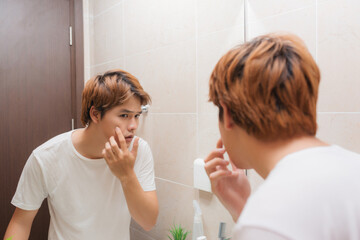 Reflection of young man in mirror checking his stubble in bathroom