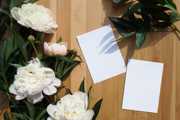 Flat lay. White card and white peonies on a wooden background. Natural light casts shadows on the plants. Great for portfolios, mockups and layouts. - 454563692