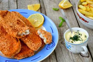  Fish and Chips/Close up of   crispy breaded  deep fried alaska pollock  fillets  with breadcrumbs served with remoulade sauce french fries  and   fresh lemons 