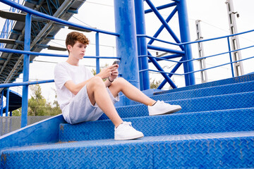 Teenager in white t-shirt on some blue stairs.