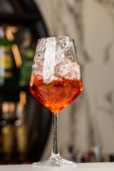 Bartender preparing on the counter Aperol Spritz, a classic refreshing Italian aperitif made mixing Aperol, Prosecco and sparkling soda.