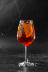 Glass of ice cold Aperol spritz cocktail served in a wine glass, decorated with slices of orange...