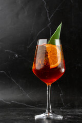 Glass of ice cold Aperol spritz cocktail served in a wine glass, decorated with slices of orange...