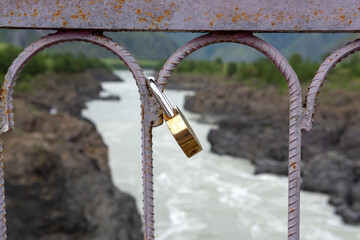 closed locks on the railing of a suspended metal bridge over the Katun River
