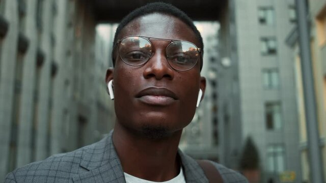 A close-up view of a handsome african american businessman looking to the camera outside on the street