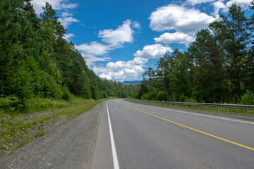 Fototapeta premium highway road and mountain peaks on the background of a blue sky with clouds