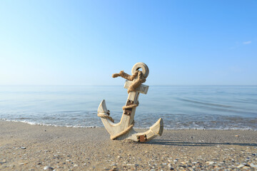 Wooden anchor with rope on sand near sea
