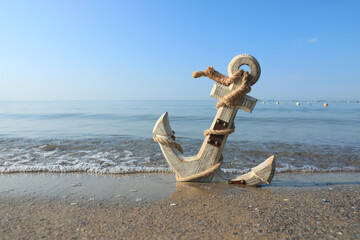 Wooden anchor with rope on sand near sea. Space for text - obrazy, fototapety, plakaty
