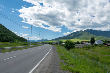 Fototapeta na wymiar highway road and mountain peaks on the background of a blue sky with clouds