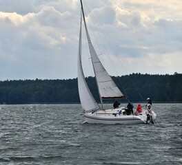 Sylwetka samotnie żeglujacego jachtu kabinowego po jeziorze. Mazury, krajobraz. © Lidia