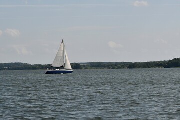 Sylwetka samotnie żeglujacego jachtu kabinowego. Mazury, krajobraz. © Lidia