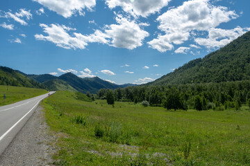 Obraz premium highway road and mountain peaks on the background of a blue sky with clouds
