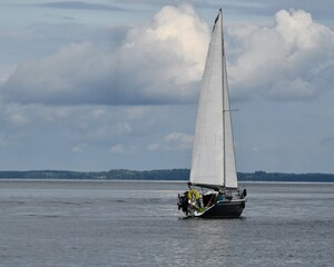 Sylwetka samotnie żeglujacego jachtu kabinowego po jeziorze Śniardwy.  Mazury, żaglówka.