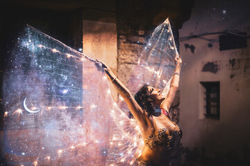 Young belly dancer with galaxy wings in a castle