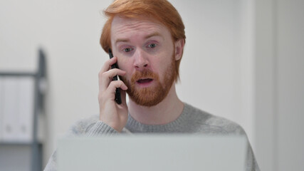 Beard Redhead Man with Laptop Talking on Smartphone 