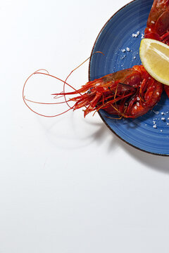 Scarlet shrimps with aromatic lemon pieces on plate