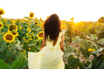 Anonymous woman in yellow dress in sunflower field