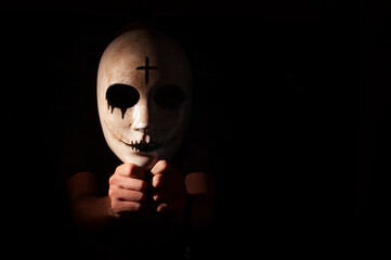 mask in hand with black background, high contrast photography. halloween concept with copyspace