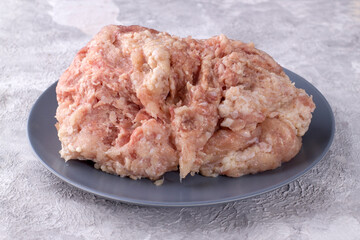 Raw chicken mince on a gray plate on a light background